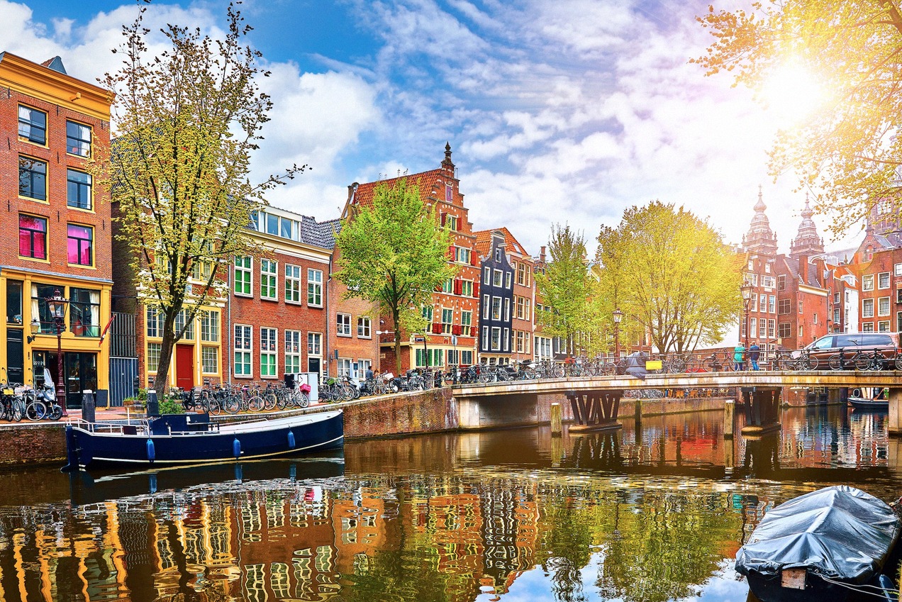 Spring on an Amsterdam canal with houseboats and a bridge